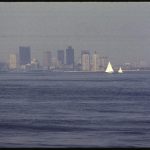 A city skyline is partly obscured by thick haze caused by air pollution.