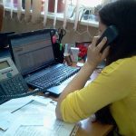 Office workers use laptops at shared desks during a collaborative working day.